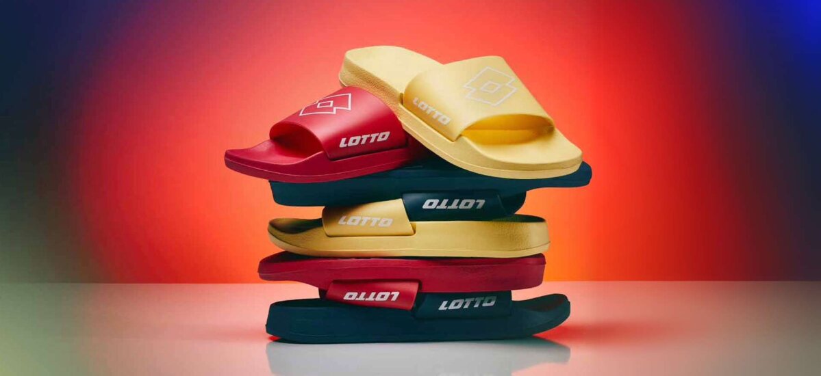 Na slici je prikazano nekoliko pari Lotto natikača koje su složene u naslagani red. Svaki par natikača je različite boje, uključujući crvenu, žutu, crnu i zelenu, s logotipom Lottoa na gornjem dijelu.